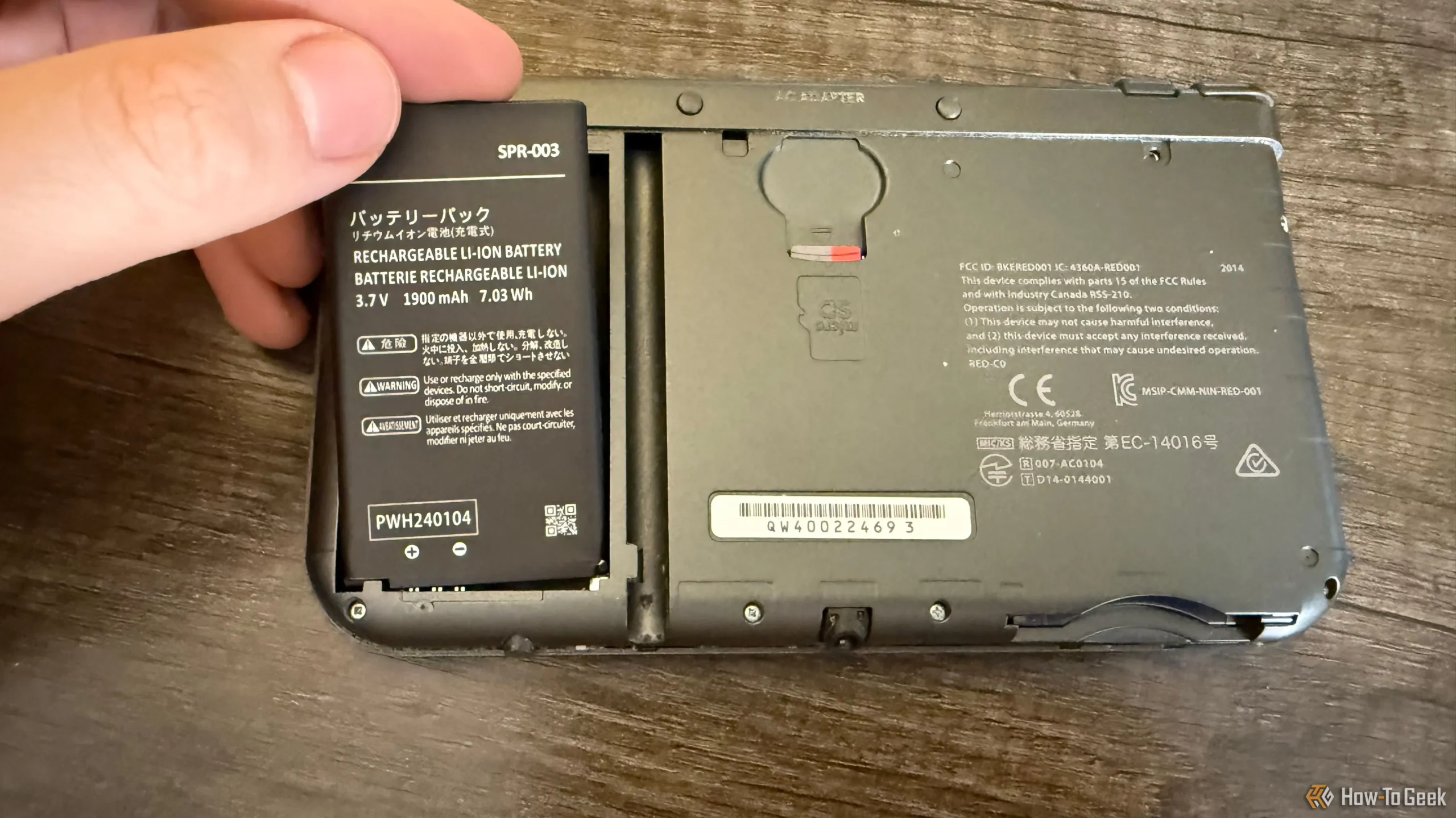 En hånd som plasserer en batteripakke i en New Nintendo 3DS XL.