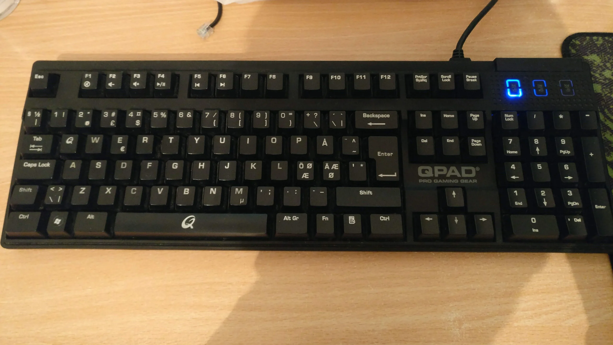 木製の机の上に置かれた QPAD MK-50 メカニカル キーボード。