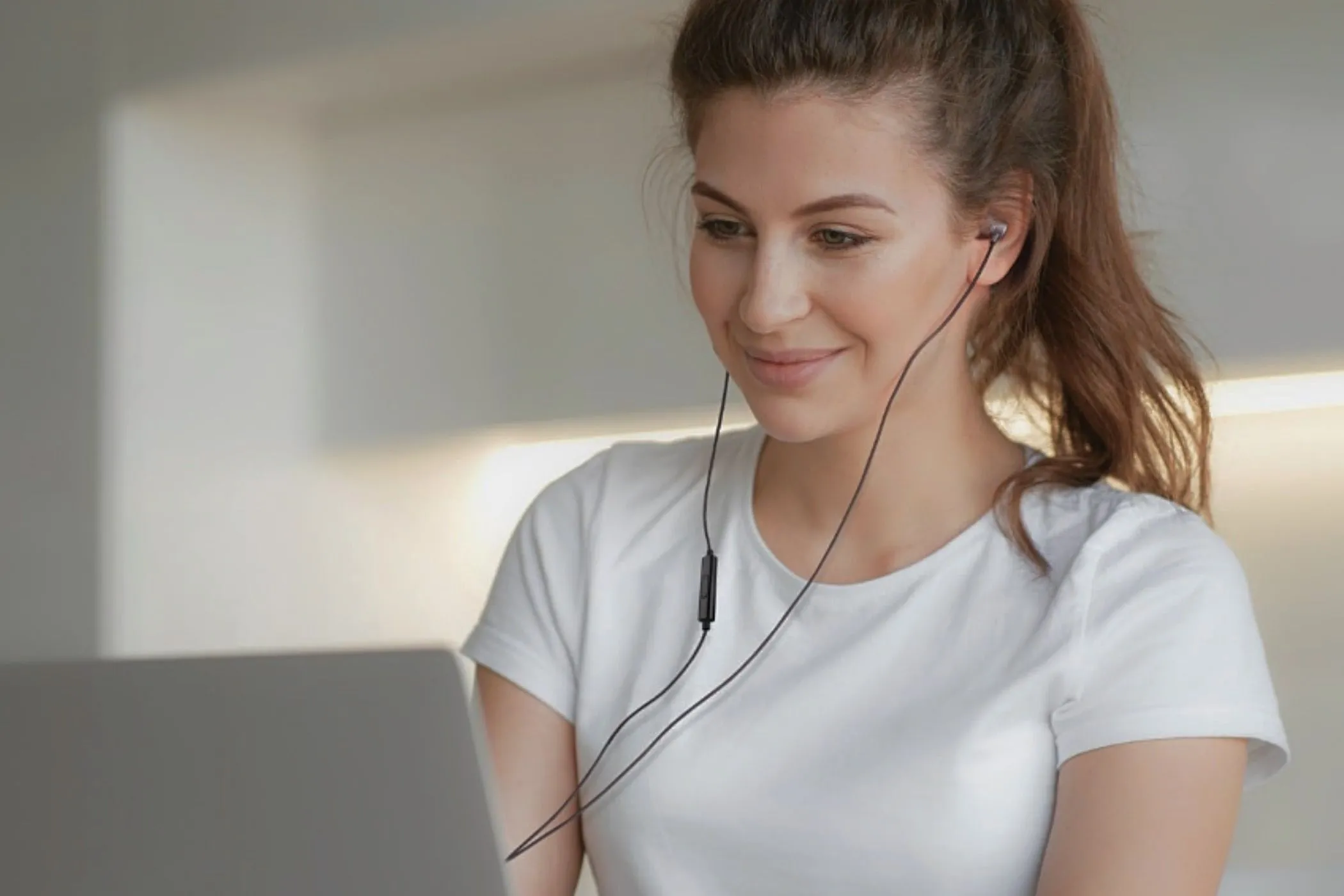 Uma mulher em seu laptop com um par de fones de ouvido UliX Rider.